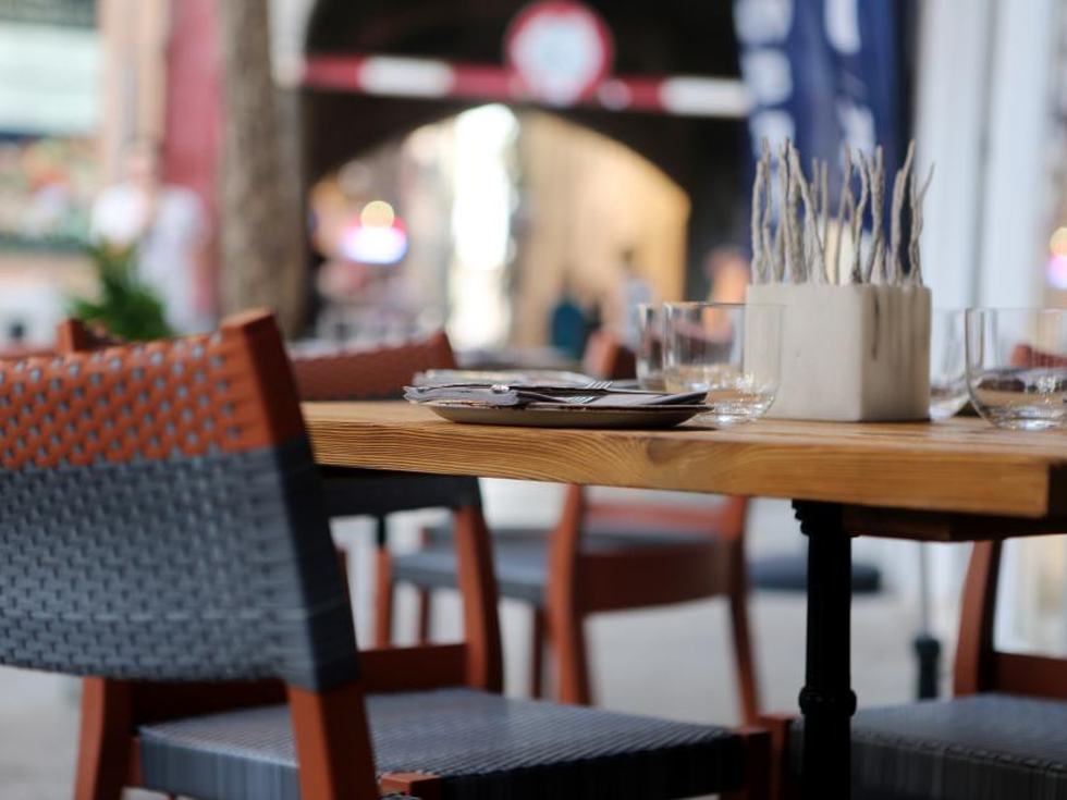 Tisch mit Stühlen und eingerollten Servietten in einem hellen Lokal